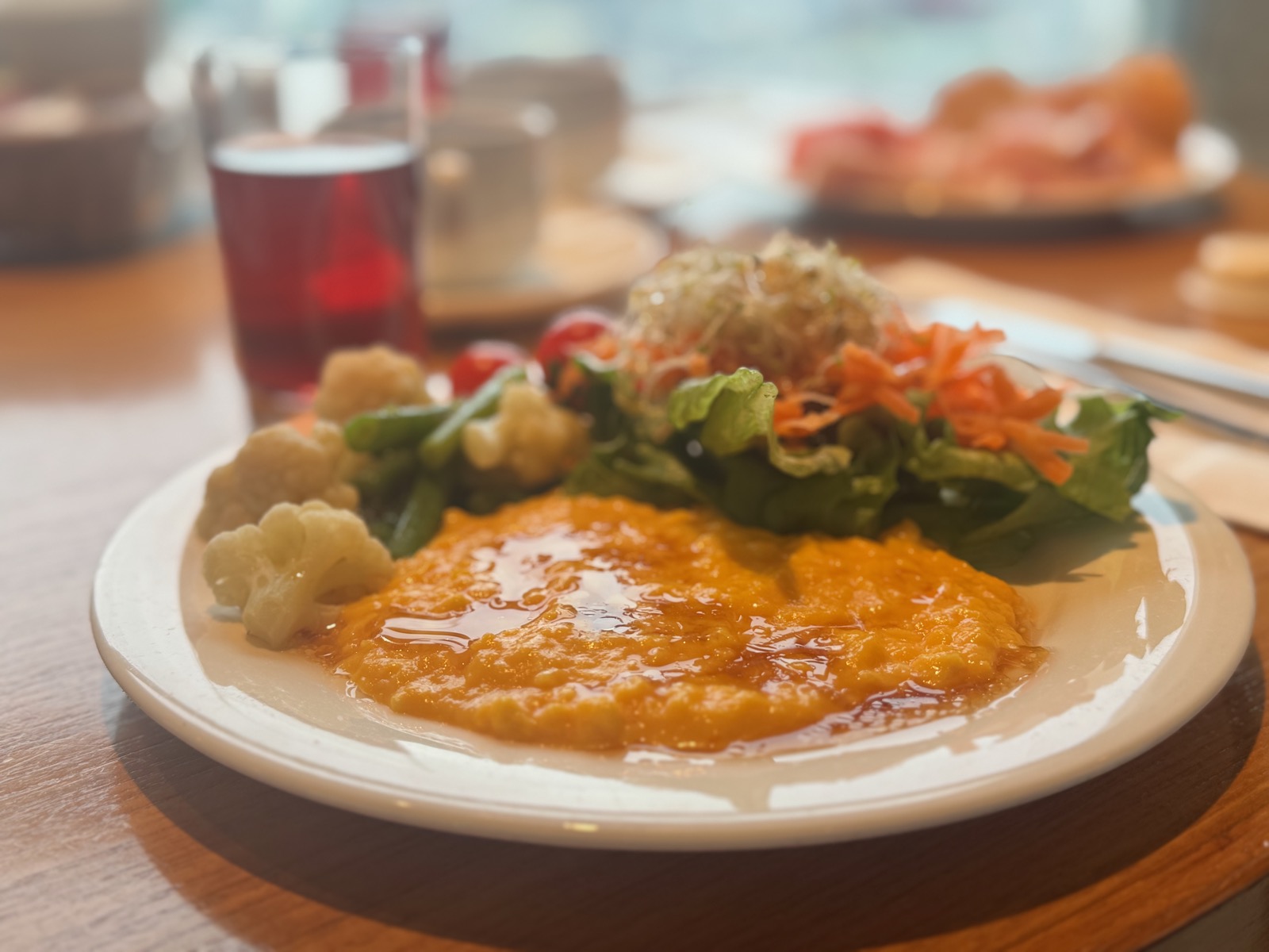 Hotel breakfast buffet plate with scrambled eggs, salad, and cauliflower