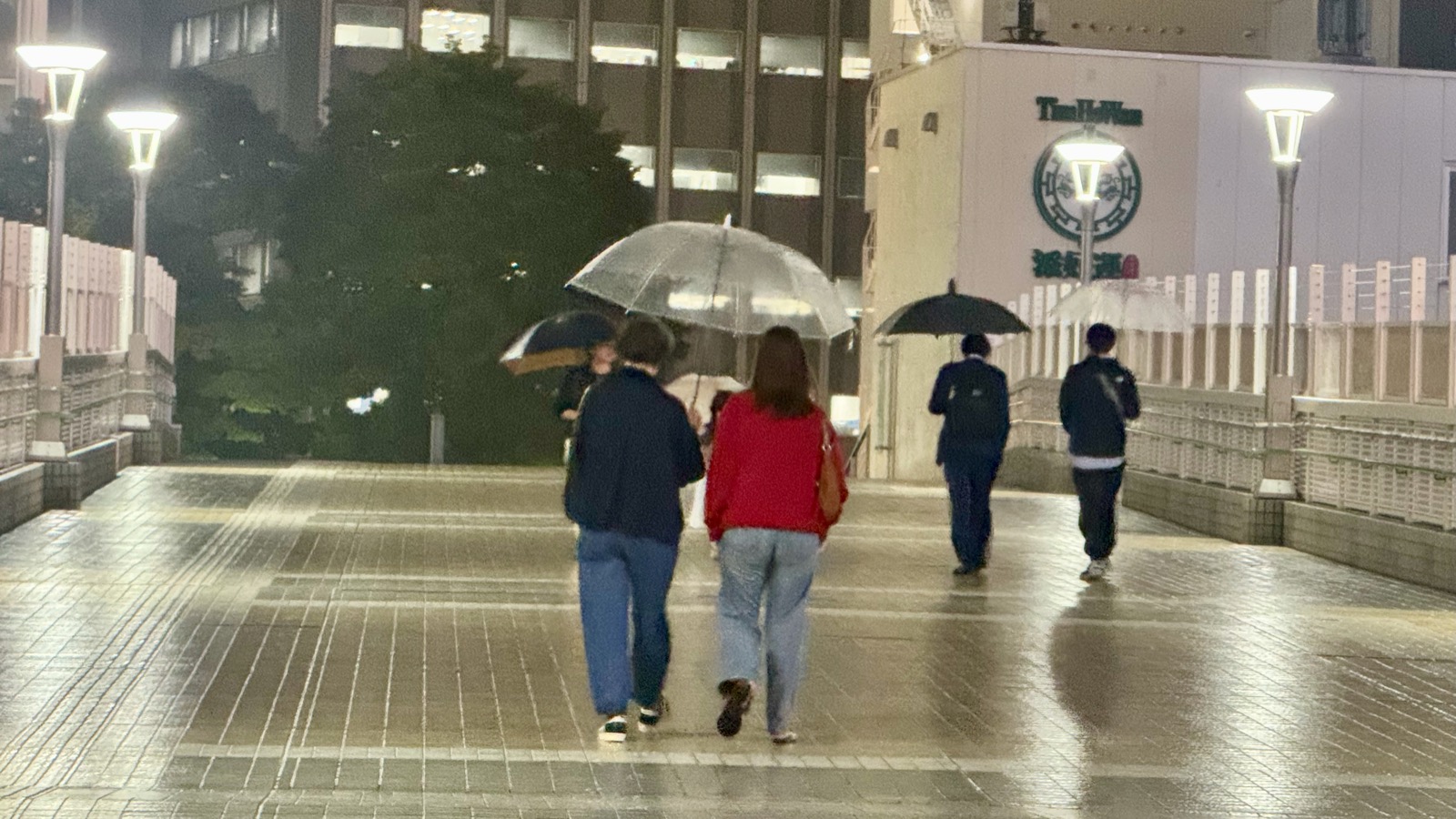 Walking home in the rain with umbrellas through Shinjuku at night